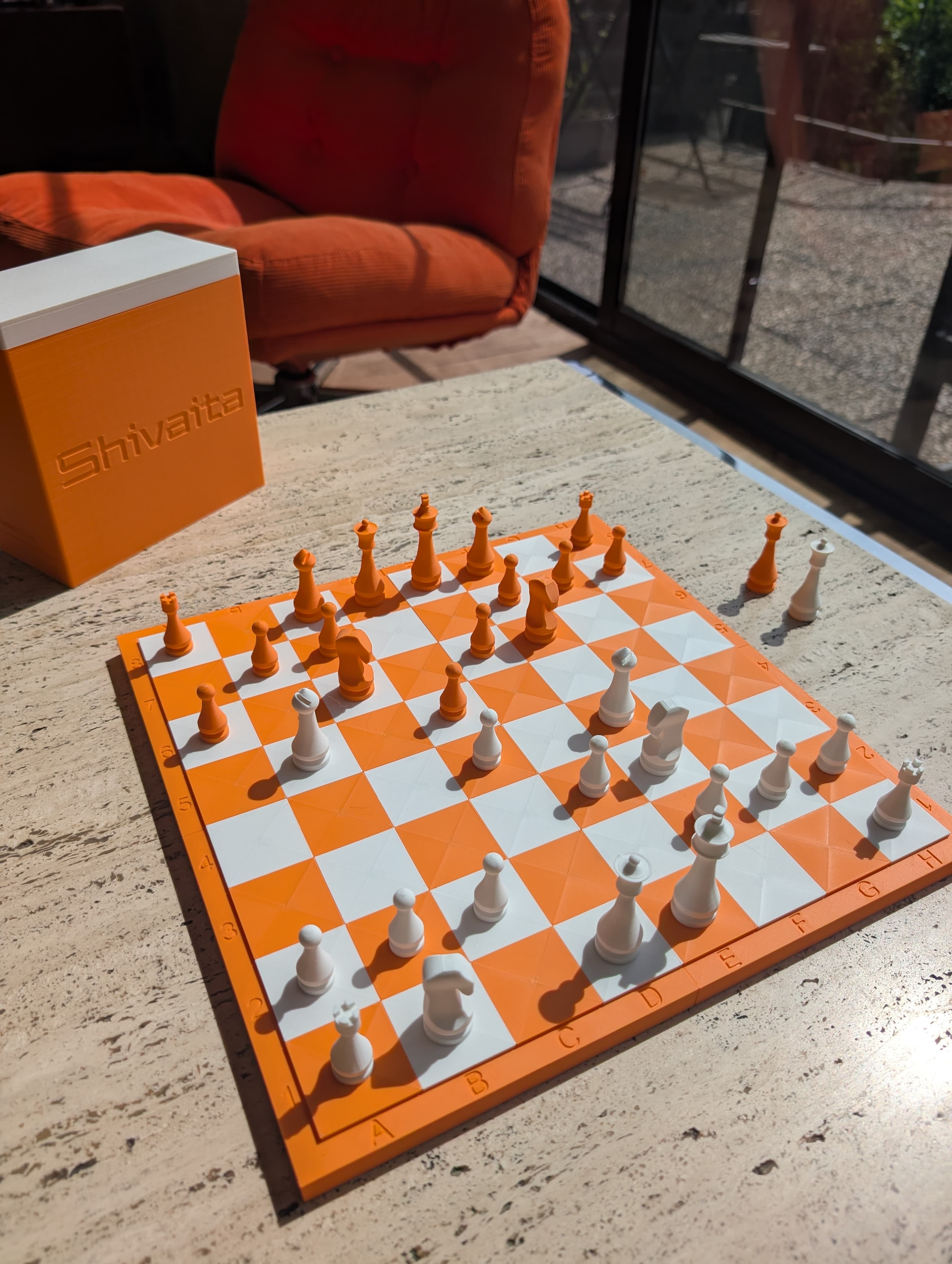 A mandarin orange and bone white printed chess board outdoors in the sun